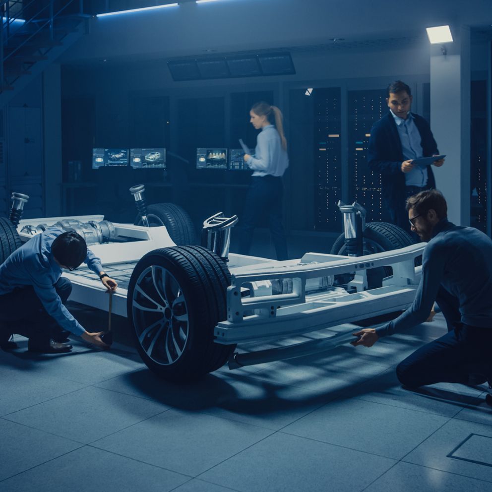 Vier Menschen laufen um Elektrofahrzeug und schauen es sich an.