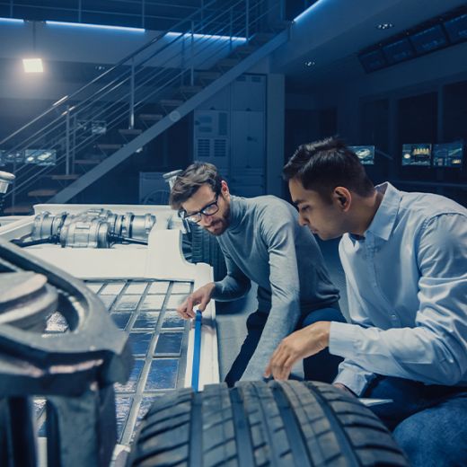 Zwei Männer schauen sich ein Fahrzeug der Zukunft an und hocken dabei.